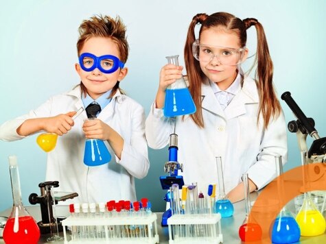 Un niño y una niña vestidos con batas de laboratorio blancas